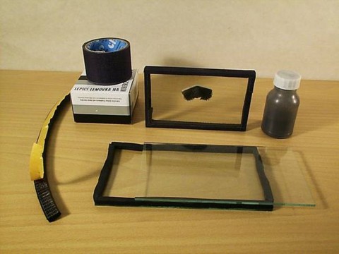 Zdenk Polk: Magnety - Obr. 1: Poteby na zhotoven oknka pro zkoumn magnetickho pole. V pozad hotov oknko s pilinkami a picvaknutm typlovm HDD magnetem. Dven samolepic tsnn z pnov gumy m prez 8 x 16 mm. Ped pilepenm ho rozstihneme na dva psky.
