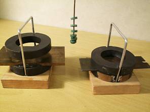 Zdenk Polk: Magnety - Obr. 1: Kruhov magnety s mosaznou a eleznou deskou v mezee. V pozad sloupec malch kruhovch vzjemn se odpuzujcch magnet na mdnm drtu.